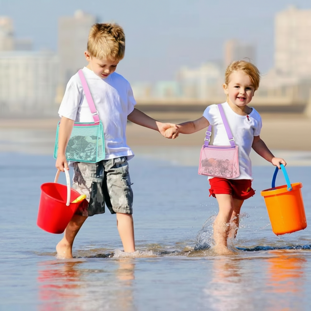 Two children wearing mesh shoulder bags while wading with beach buckets