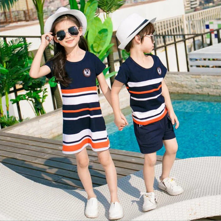 Two children holding hands in a navy striped dress and matching T-shirt with shorts