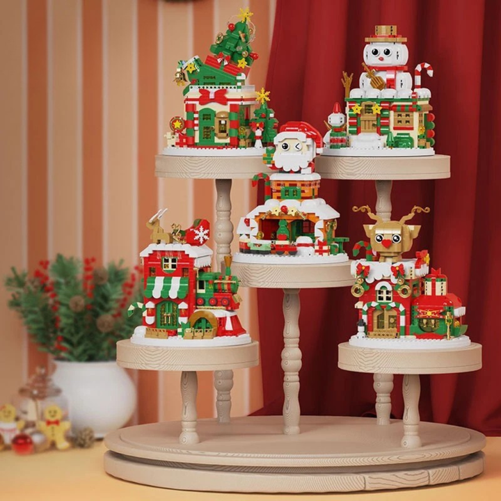 Five Christmas block buildings topped with Santa, snowman, tree, reindeer and sleigh designs