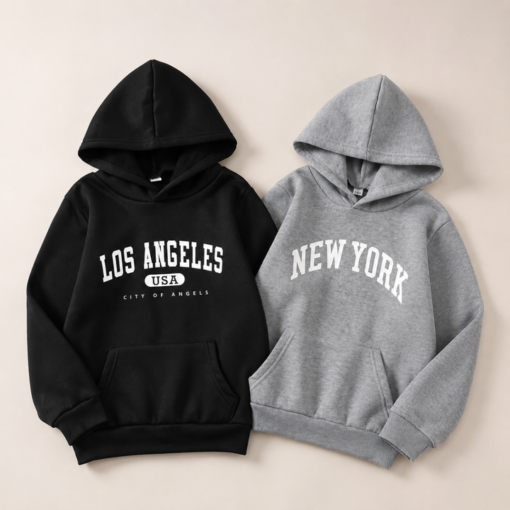 Black Los Angeles and gray New York hoodies laid side by side.