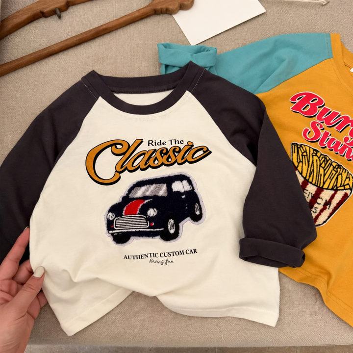 Cream classic car graphic shirt with black raglan sleeves beside a yellow fries shirt