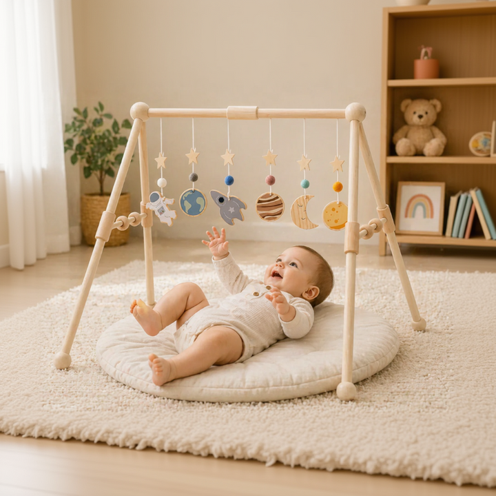 Baby reaching toward space-themed hanging toys on a Classical wooden baby gym frame.