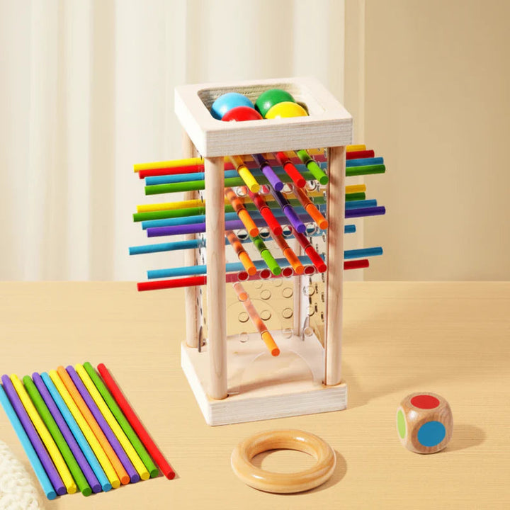 Clear-sided wooden stick tower with colored balls, loose sticks, a wooden ring, and a die.