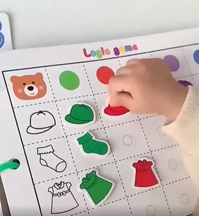 Child matching clothing pieces to outlines and colors in an activity book