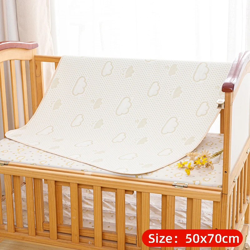 Cloud-print mattress protector labeled 50 x 70 cm draped in a wooden crib