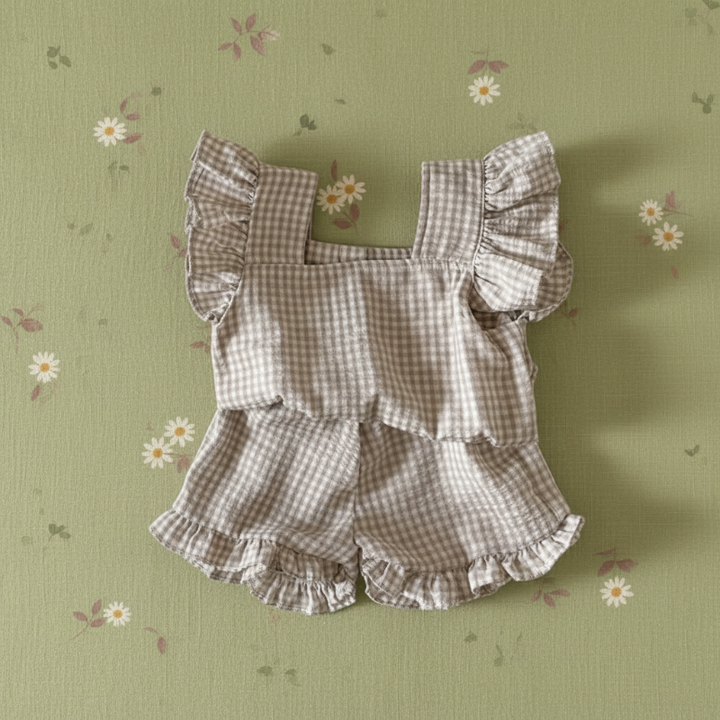 Coffee gingham ruffle top and matching bloomers on a green daisy-print background