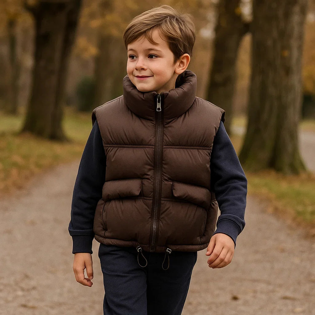 Child wearing a coffee-brown puffer vest with a high collar on a wooded path