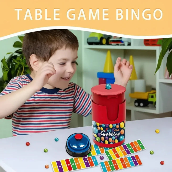 Child beside a tabletop color bingo game with a red ball container, blue bell, and colorful cards