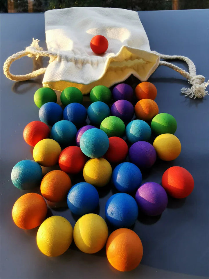 Multicolored wooden balls arranged in front of a cream drawstring bag