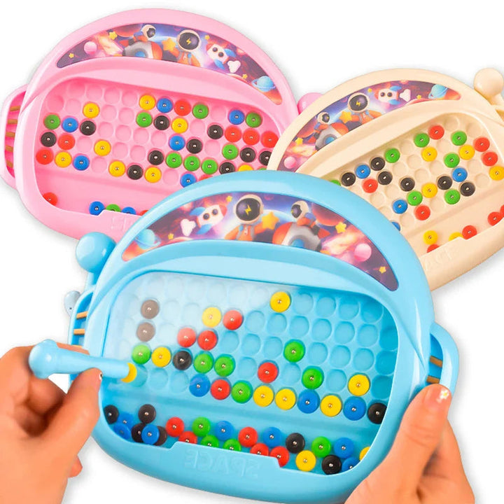 Blue, pink, and cream magnetic bead drawing boards, with a hand using the blue board&