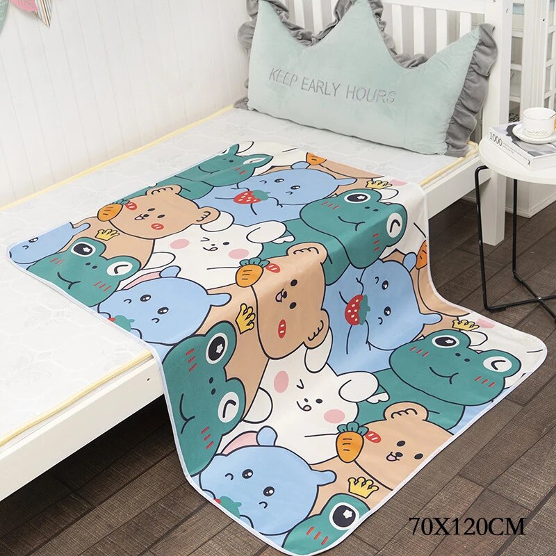 Changing mat with large, colorful cartoon animals draped over a bed, labeled 70 x 120 cm.