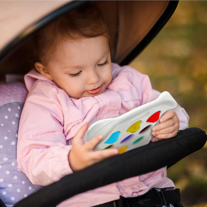 Child holding a colorful sensory button toy while seated in a stroller
