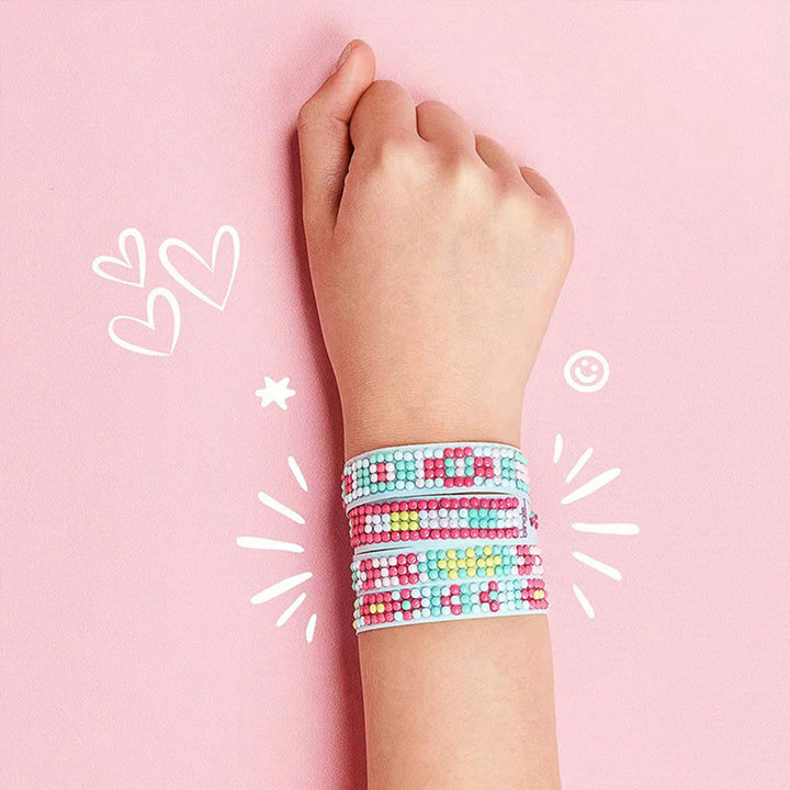 Wrist wearing several colorful gem bracelets against a pink background