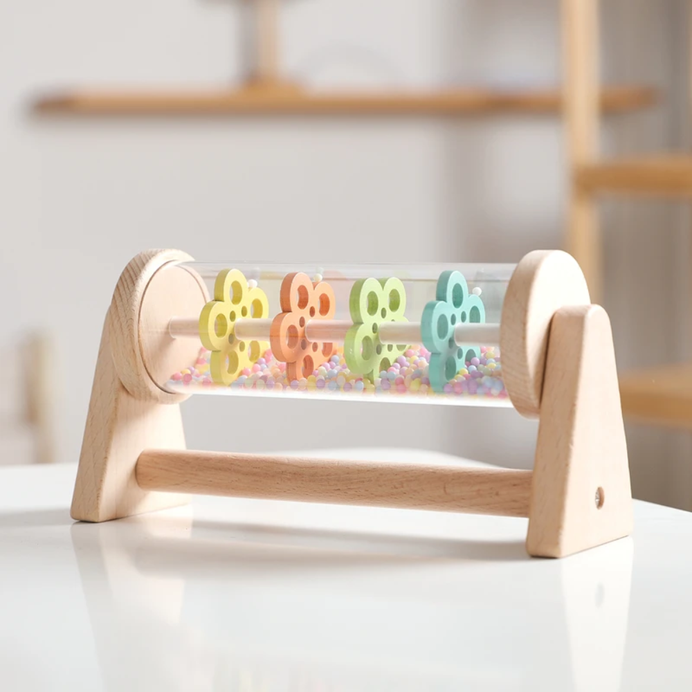 Wooden rain sound toy with colorful wheels displayed on a white tabletop.