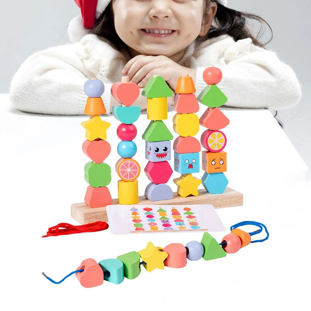Child smiling behind a wooden stand stacked with colorful shape beads, with a pattern card and lacing cord.