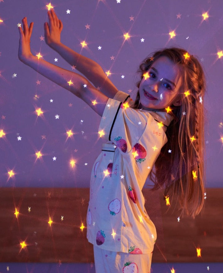 A child reaching toward colorful star projections on a wall.