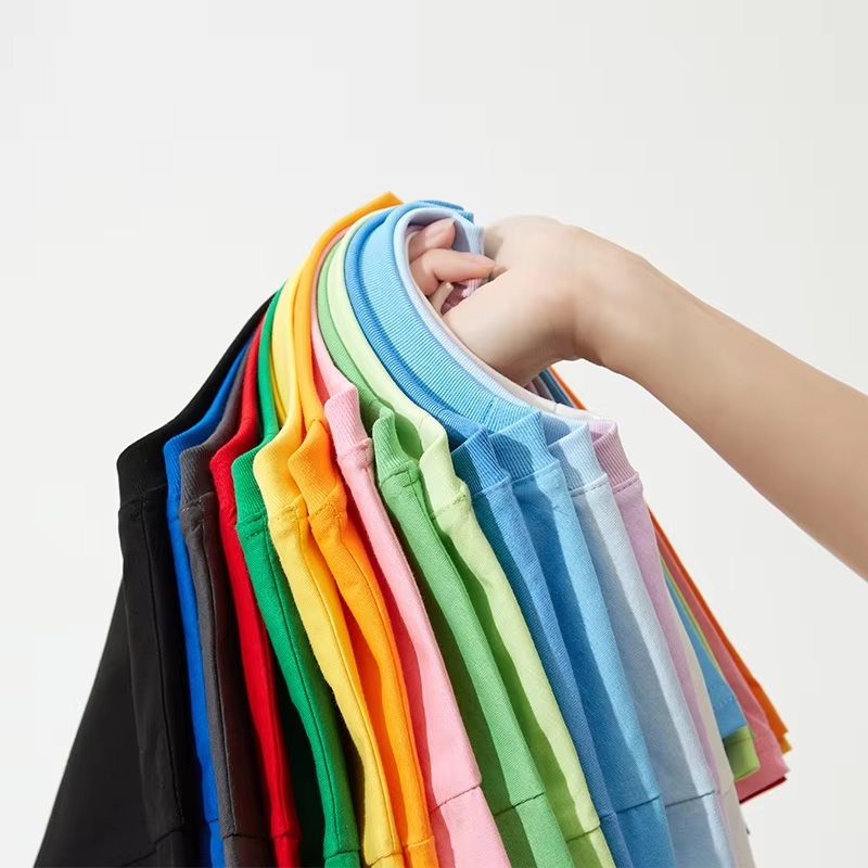 Hand holding colorful T-shirts to show their round necklines