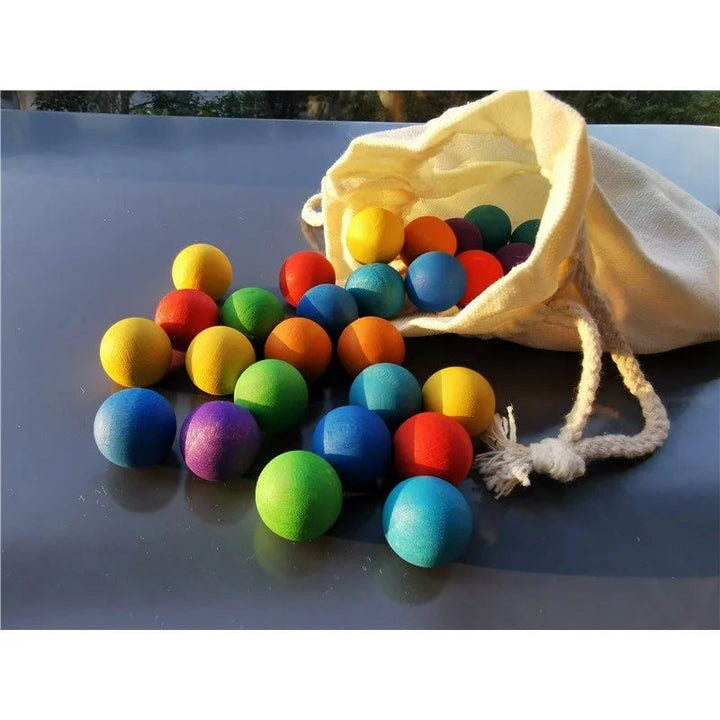 Assorted wooden balls clustered in front of an open cream drawstring bag
