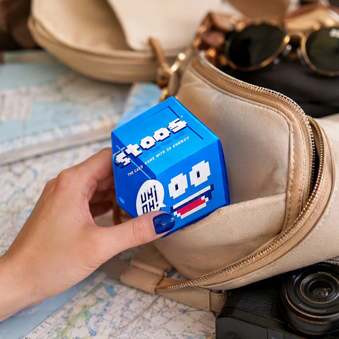 Compact blue card game box held over an open zippered bag
