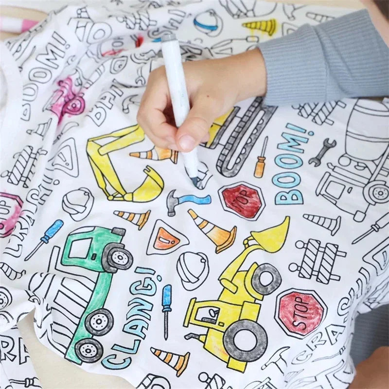 Close-up of a hand coloring construction vehicles on white pajama fabric