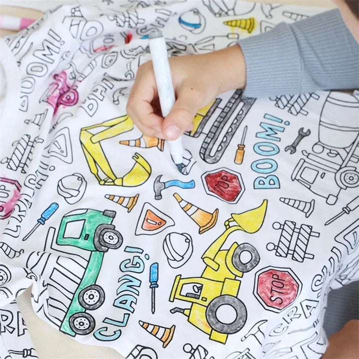 Close-up of a hand coloring construction vehicles on white pajama fabric