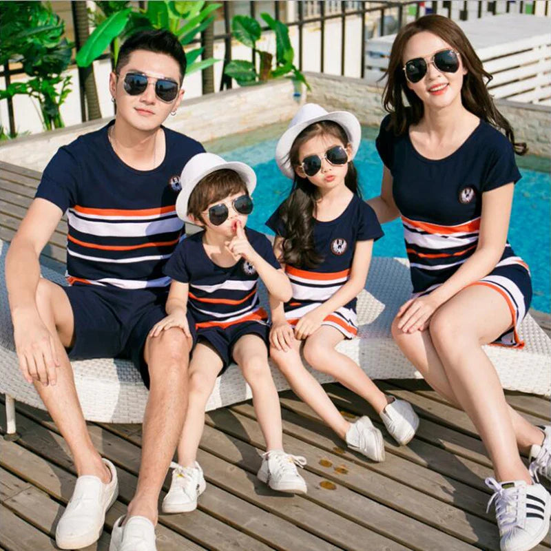 Parents and two children seated beside a pool in coordinated striped clothing