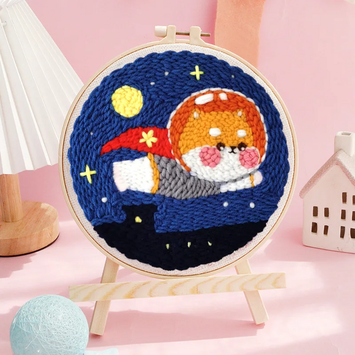 Corgi astronaut punch needle hoop with a red scarf and yellow stars against a dark blue sky