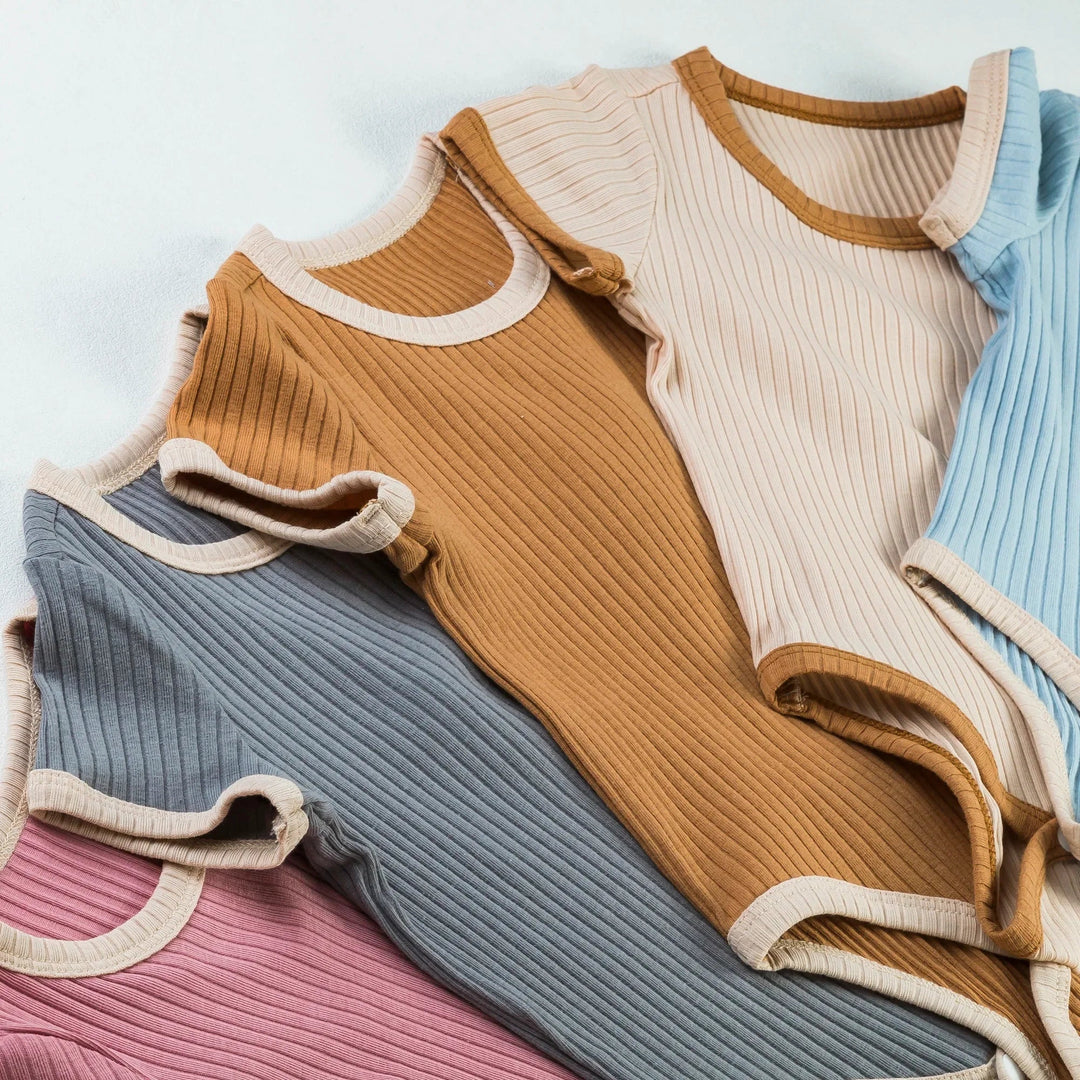 Overlapping ribbed baby rompers in pink, gray, brown, beige, and blue