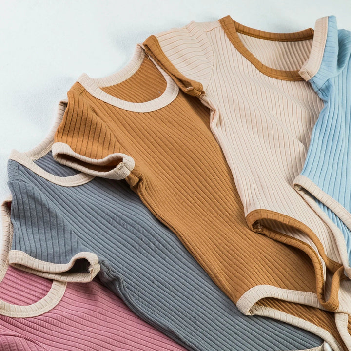 Overlapping ribbed baby rompers in pink, gray, brown, beige, and blue