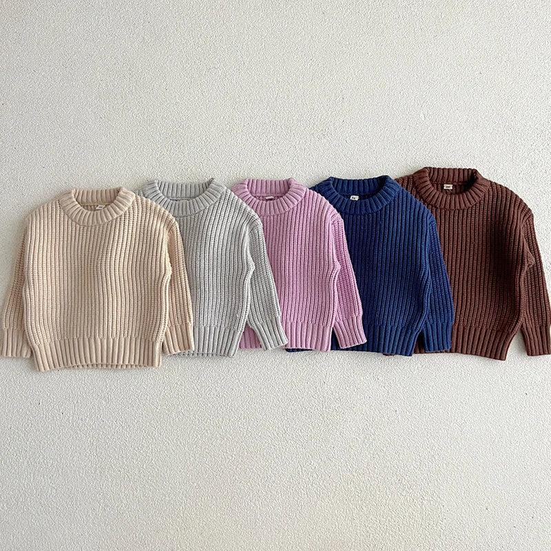 Front views of five long-sleeve cotton sweaters with round necklines and ribbed hems.
