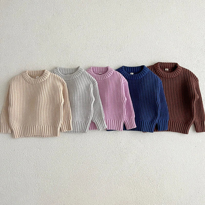 Front views of five long-sleeve cotton sweaters with round necklines and ribbed hems.