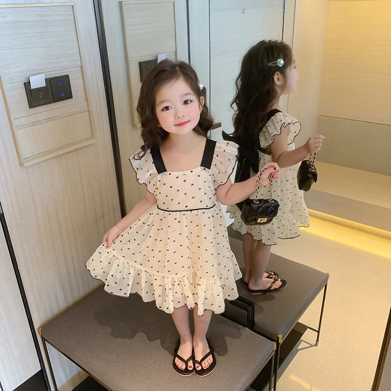 Girl modeling the ruffle-trim heart dress beside a mirror