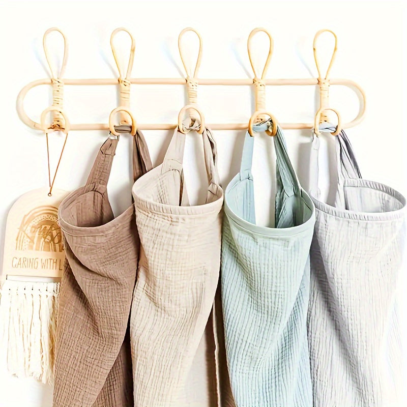 Four cotton nursing covers hanging by their neck straps from wall hooks