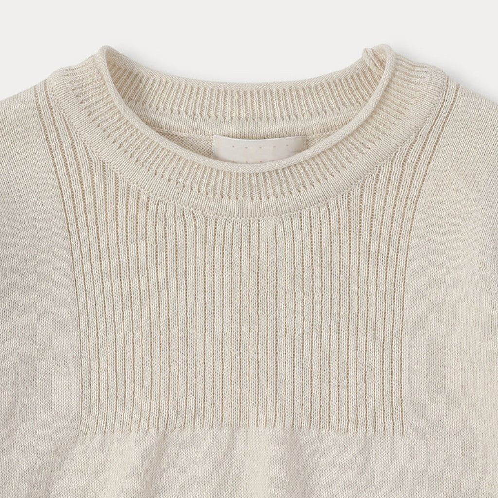 Ribbed crew neckline and vertical-knit chest panel on the cream sweater