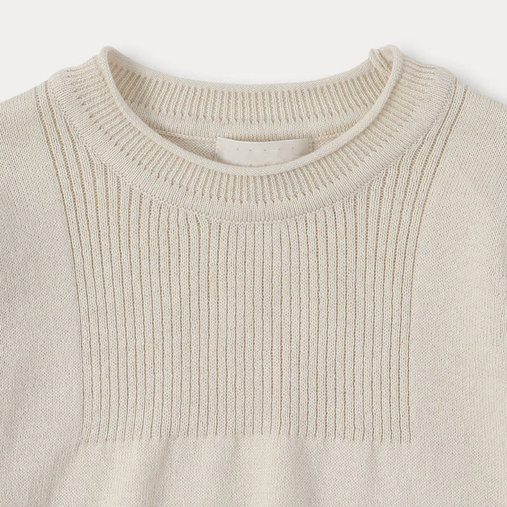 Ribbed crew neckline and vertical-knit chest panel on the cream sweater