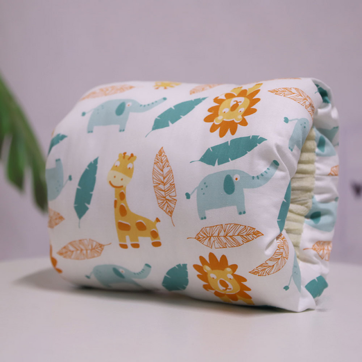 Nursing pillow printed with lions, giraffes, elephants, and leaves.