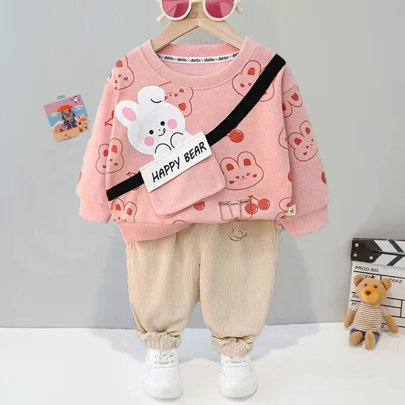 Pink bear-print sweater and beige pants displayed together on a hanger