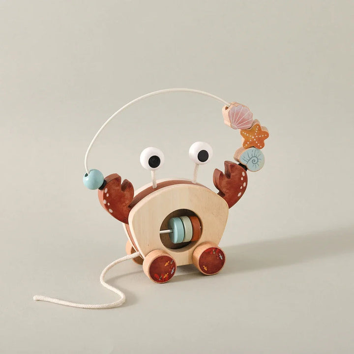 Wooden crab pull toy standing on a tabletop with sea-themed beads and a loose pull cord
