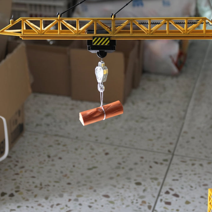 Crane hook holding an orange cylindrical toy load beneath the boom.