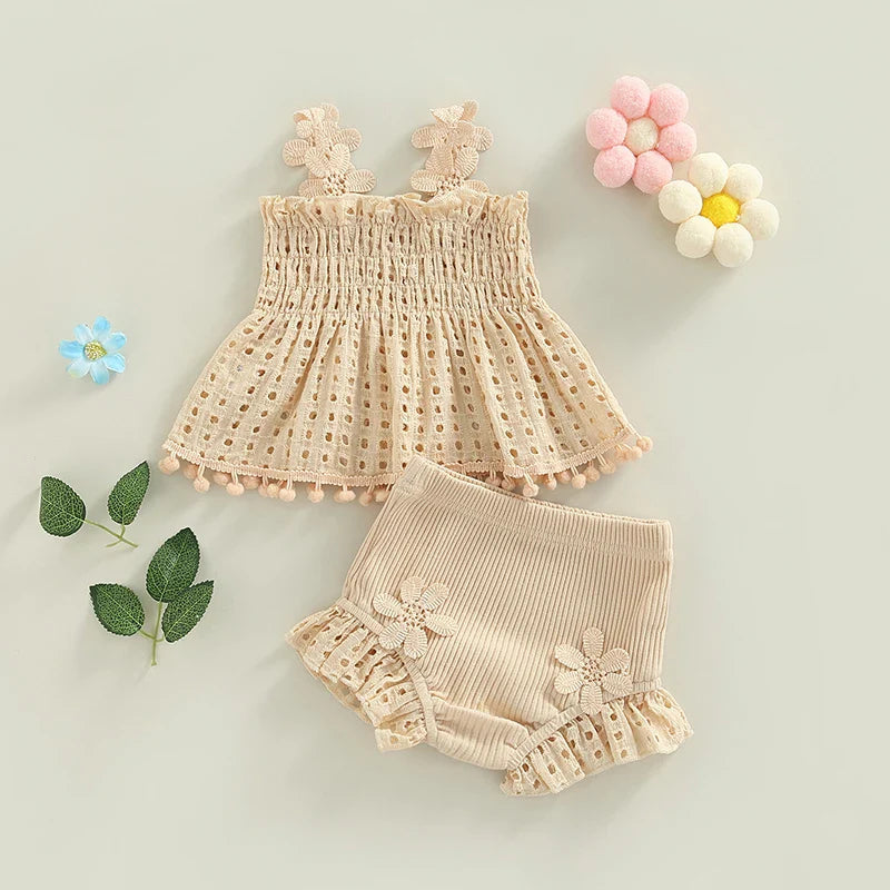 Cream baby outfit with a floral-strap top and matching ribbed shorts laid out with flower decorations