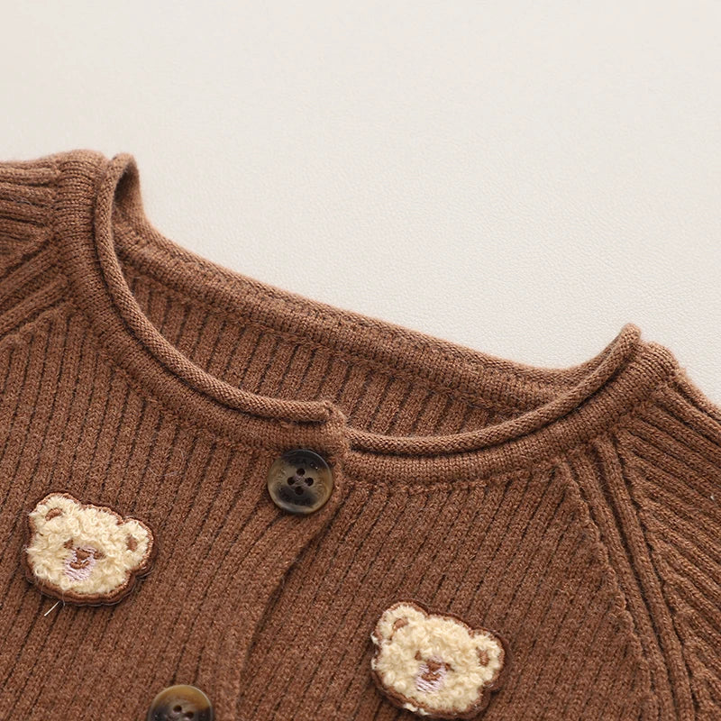 Close-up of the brown sweater neckline, buttons, and cream bear accents
