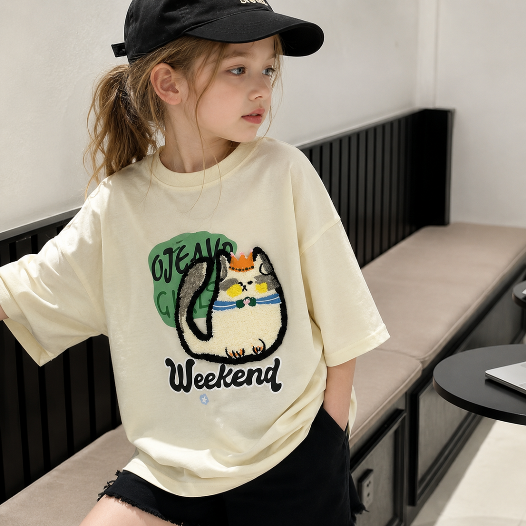 Child wearing the cream cat-print tee with its roomy short sleeves visible
