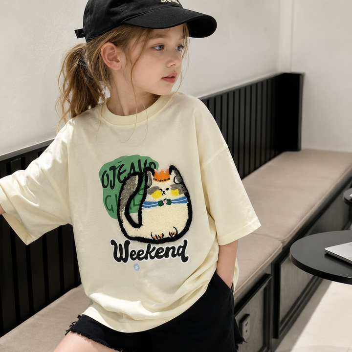 Child wearing the cream cat-print tee with its roomy short sleeves visible