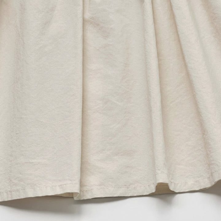 Close-up of the cream cotton blouse fabric, soft folds, and bottom hem