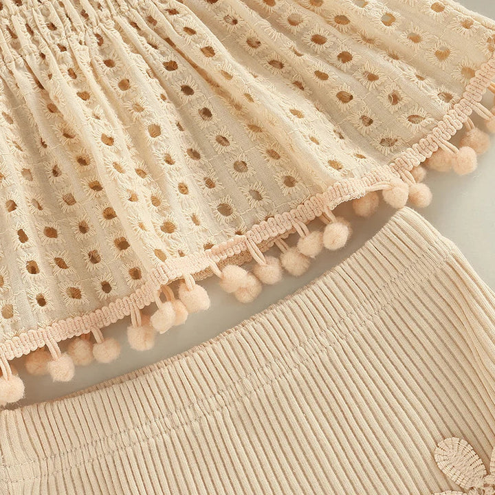 Cream eyelet top hem with bobble trim above the ribbed shorts waistband