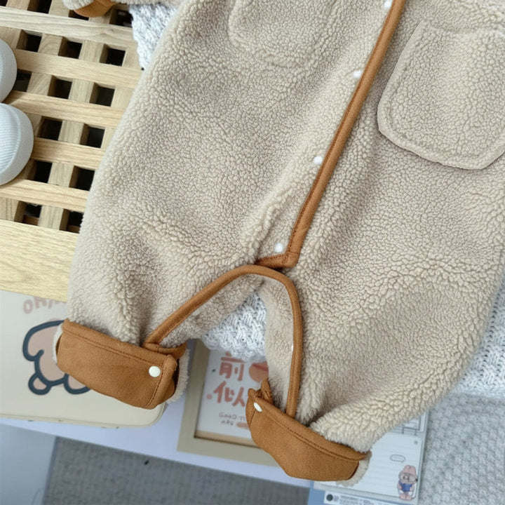Cream fleece side of a baby romper showing leg snaps and brown fold-back cuffs