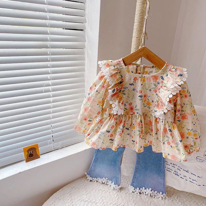 Cream floral long-sleeve blouse and blue flared pants displayed on a hanger