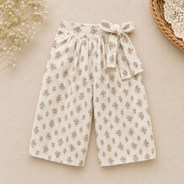 Cream wide-leg pants with a small floral pattern and a matching waist bow
