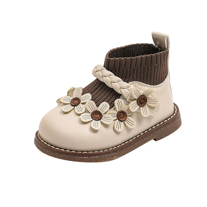 Side view of a Cream White ankle boot with flower appliqués, a braided band, and a back pull tab.