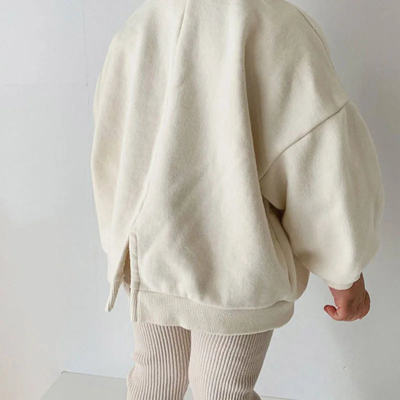 Back view of a child wearing a cream sweatshirt with dropped shoulders and a relaxed fit